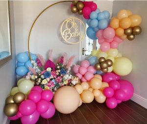 Multicoloured balloons and baby shower backdrop and sign